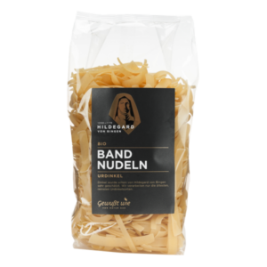 Verpackung mit bio Bandnudeln aus Ur-Dinkel in transparenter Folie, mit goldener Schrift und Abbildung von Hildegard von Bingen.