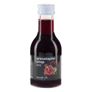Braune Glasflasche mit schwarzer Etikette, gefüllt mit bio Granatapfelsirup, glänzender Deckel.