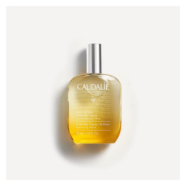 Glasflasche mit einem goldenen Öl und silbernem Deckel, beschriftet mit "Huile de Soin Soleil des Vignes" von Caudalie.