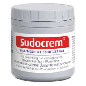 Runde, graue Dose mit Sudocrem Schutzcreme und rotem Schriftzug, behandelt Hautprobleme.