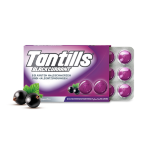 Paket mit Tantills Blackcurrant Halspastillen auf lila Hintergrund, umgeben von schwarzen Johannisbeeren und einem frischen Blatt.