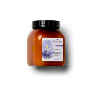 Glasbehälter mit orangefarbenem Badesalz, Label mit dem Titel 'Sternenmeer' von Dr. Klade, betont Entspannung.