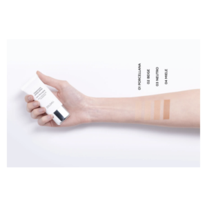 Eine Hand hält eine Tube Flüssigfoundation, daneben sind vier Farbstriche auf dem Unterarm abgebildet.