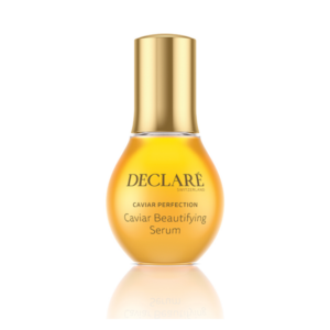 Flasche mit Caviar Beautifying Serum von DECLARÉ, orangefarben mit goldenem Deckel, reflektierender Oberfläche.